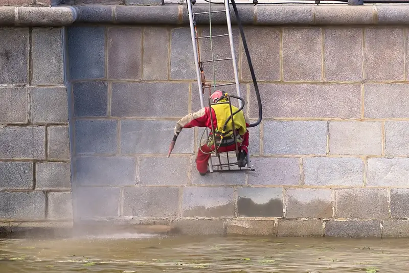 Sableur encordé qui décape un mur de pierre
